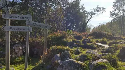 two signs on a trail in a field with rocks at Petrines Gjestgiveri in Norddal