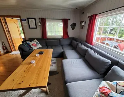 a living room with a couch and a wooden table at Høstkos og ro på Budor, 4 roms hytte med peis og wifi in Nordset