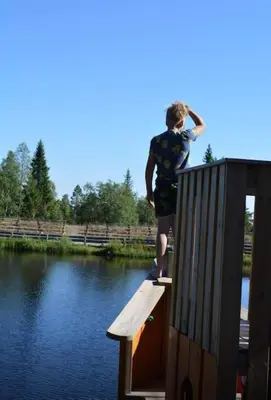 a young man standing on a wooden ramp next to a body of water at Høstkos og ro på Budor, 4 roms hytte med peis og wifi in Nordset