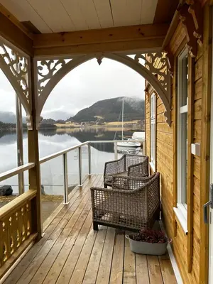 a porch with two chairs and a view of the water at Handelsmannens hus ved Otnesbrygga, Valsøyfjord in Otnes