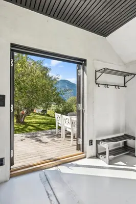a patio with a table and chairs and a large window at Jordeplegarden holiday home - Part of a farm - Two buildings - Close to Flåm in Lærdalsøyri