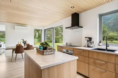 a kitchen with wooden cabinets and a large window at Jordeplegarden holiday home - Part of a farm - Two buildings - Close to Flåm in Lærdalsøyri