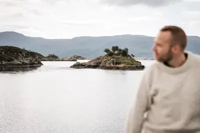 a man standing in front of a body of water at Quality Hotel Ulstein in Ulsteinvik