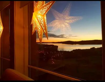 a window with a christmas star hanging from it at Fjordcabin Panoramic view Near Bergen 3 sleepingroom in Forland