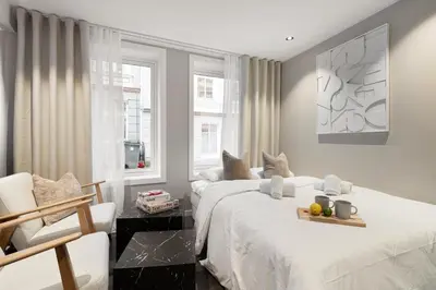 a bedroom with two beds and a chair and two windows at Renovated jan 24 - Queen beds - Behind Bryggen in Bergen