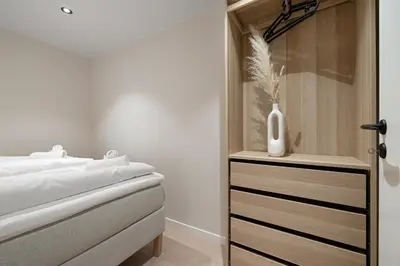 a bedroom with a bed and a vase on a dresser at Renovated jan 24 - Queen beds - Behind Bryggen in Bergen