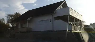 a white house with a black roof and stairs at Hus ved sjøen in Bakken