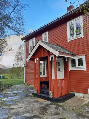 a red house with a front porch and white windows at Flatheim in Viksdalen