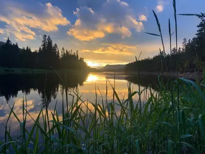 a sunset over a lake with the sun setting at ElveRo Lodge in Trysil