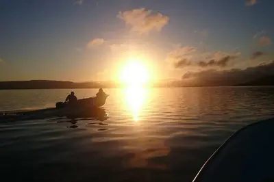 a man in a boat on the water at sunset at Edvinstua Solbakken Feriehus in Fevåg