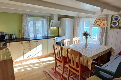 a kitchen with a table and chairs in a kitchen at Edvinstua Solbakken Feriehus in Fevåg