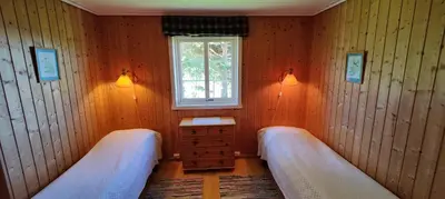 a small room with two beds and a window at Strandstua Solbakken Feriehus in Fevåg