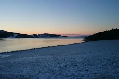 a large body of water with snow on the ground at Strandstua Solbakken Feriehus in Fevåg