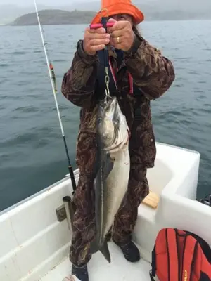 a man holding a fish on a boat at Strandstua Solbakken Feriehus in Fevåg