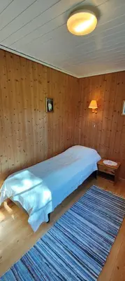 a bedroom with a bed with a blue comforter and a rug at Strandstua Solbakken Feriehus in Fevåg
