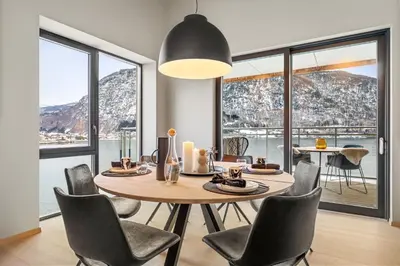 a dining room with a table and chairs and windows at Toppleilighet på bryggen i Sogndal med fantastisk utsikt in Sogndal
