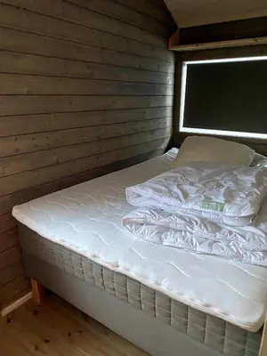 a bed in a room with a wooden wall at Hito - cabin between Flå and Eggedal in Flå