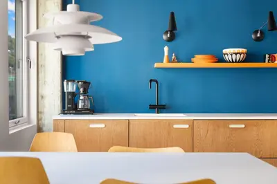 a kitchen with a blue wall and a table with chairs at Unique gem overlooking the world famous Bryggen in Bergen