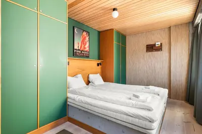 a bedroom with a bed with white sheets at Unique gem overlooking the world famous Bryggen in Bergen