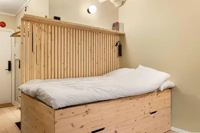a bed in a room with a wooden headboard at Fresh studio apartment, a short walk from Bryggen in Bergen