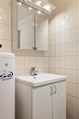 a white bathroom with a sink and a mirror at Fresh studio apartment, a short walk from Bryggen in Bergen
