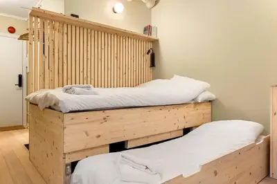 two twin beds in a room with wooden walls at Fresh studio apartment, a short walk from Bryggen in Bergen