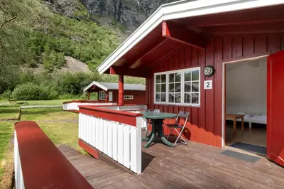 a red cabin with a table on a deck at Utladalen Camping in Årdal