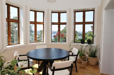 a dining room with a table and chairs and windows at Luxury Historic Villa with private coastline in Bergen