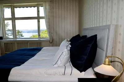 a bed with blue and white pillows and a window at Luxury Historic Villa with private coastline in Bergen
