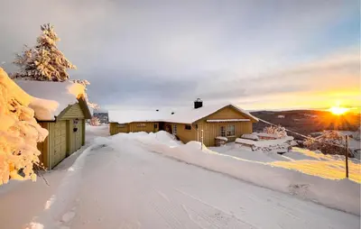 a cabin in the snow with the sunset in the background at Amazing Home In Svingvoll in Svingvoll