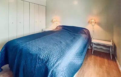 a bedroom with a bed with a blue blanket on it at Amazing Home In Svingvoll in Svingvoll