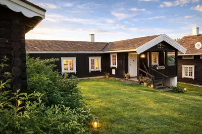 a house with a grass yard in front of it at Smie på sjarmerende og historisk gård in Baukål
