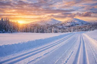 a snow covered road with the sun setting in the mountains at Smie på sjarmerende og historisk gård in Baukål