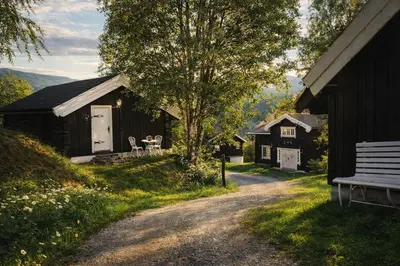 a gravel road in front of a barn with a bench at Sjarmerende tømmerhytte på gårdstun in Baukål