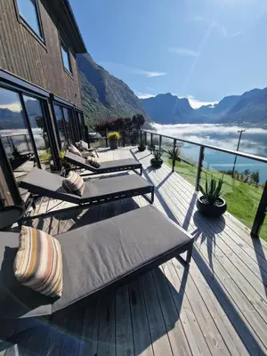 a deck with chaise lounges and a view of the ocean at Flo Bellevue in Stryn