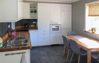 a kitchen with white cabinets and a wooden table at Lovely Home In Bjordal With Kitchen in Bjordal