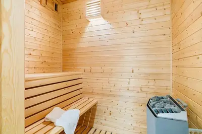 a wooden sauna with a bench and a trash can at Waterfront Villa w/Boat&kayaks. 15min from Bergen in Foldnes