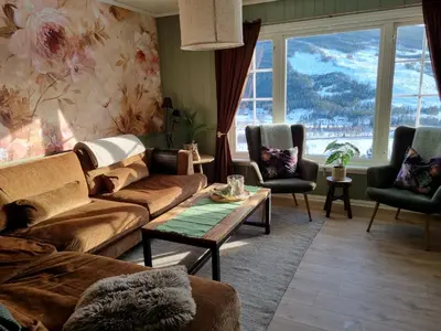 a living room with couches and chairs and a large window at Solhaug in Torpo