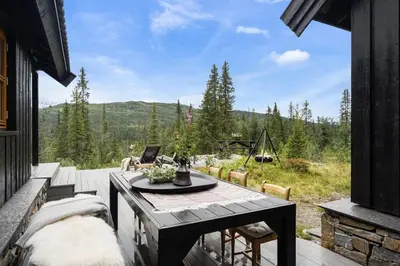 a patio with a table and a view of the mountains at Your Ideal Getaway Awaits in This Charming Cabin Retreat in Nord Torpa