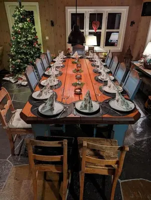 a long wooden table with chairs and a christmas tree at Your Ideal Getaway Awaits in This Charming Cabin Retreat in Nord Torpa