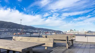 two wooden benches on a pier with a cruise ship in the background at Penthouse apartment in Bergen in Bergen