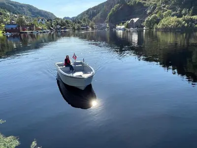 a man sitting in a boat on a lake at Sjötun Fjord Cabin, with boat in Stanghelle