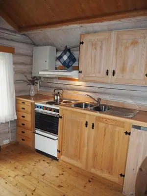 a kitchen with wooden cabinets and a sink and a stove at Gamlestogo, Rønlund Hyttepark in Ron