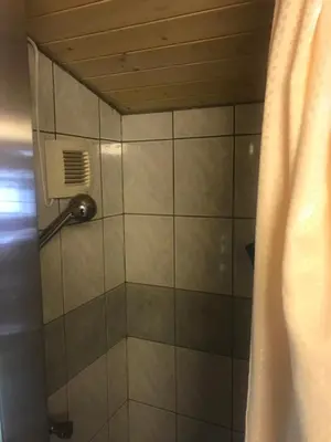 a shower with a shower head in a bathroom at Gamlestogo, Rønlund Hyttepark in Ron
