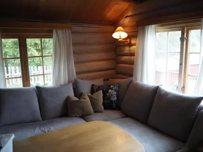 a couch sitting in a living room with windows at Gamlestogo, Rønlund Hyttepark in Ron