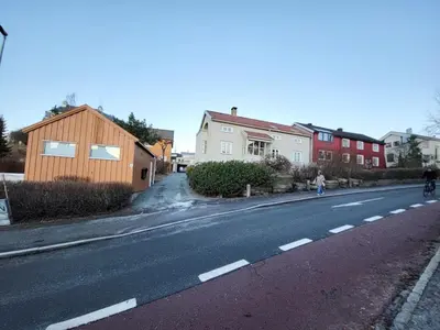 a person riding a bike down a street with houses at Mercury House, Cathedral View ! Free Parking ! in Trondheim