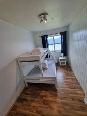 a bedroom with a bunk bed in the corner of a room at Feriehus nede ved sjøen inntil 6 pers in Vestnes