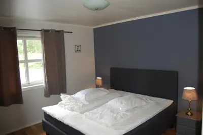 a bedroom with a bed with white sheets and a window at Feriehus nede ved sjøen inntil 6 pers in Vestnes