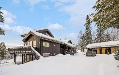 a house in the snow with a car parked in the driveway at Beautiful Apartment In Meråker in Meråker