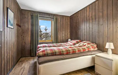 a bedroom with wooden walls and a bed with a window at Beautiful Apartment In Meråker in Meråker